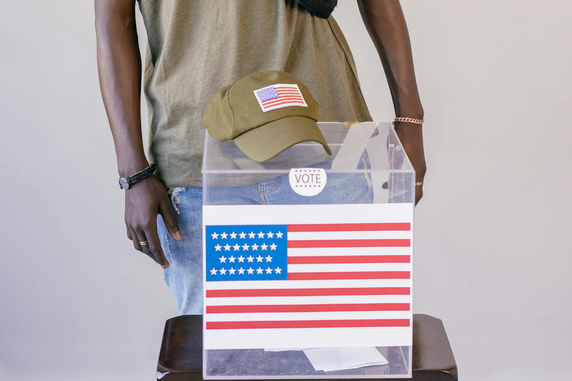 Adult voter standing by a ballot box with American flag, symbolizing democracy and election participation.