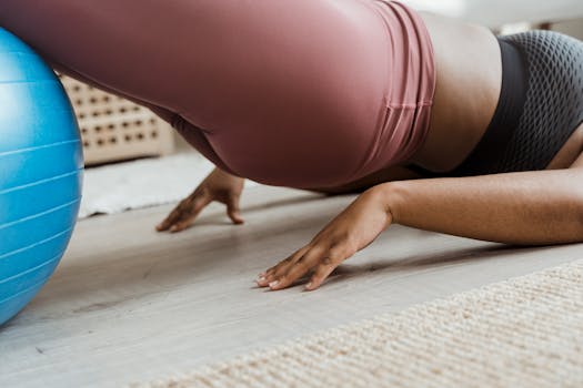 Close-up of a woman working out indoors using a fitness ball. Focus on balance and core strength.