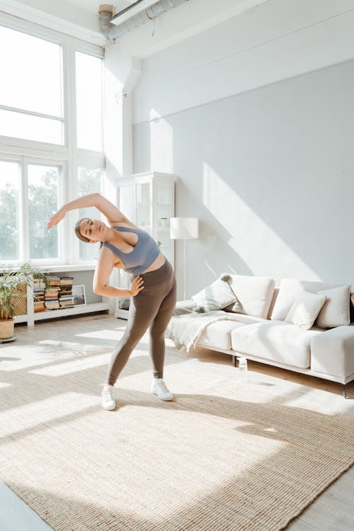 A Woman in Activewear Stretching Her Arms at Home