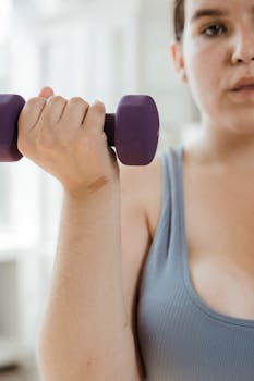 Close-up of a plus size woman lifting a dumbbell, promoting fitness and body positivity.