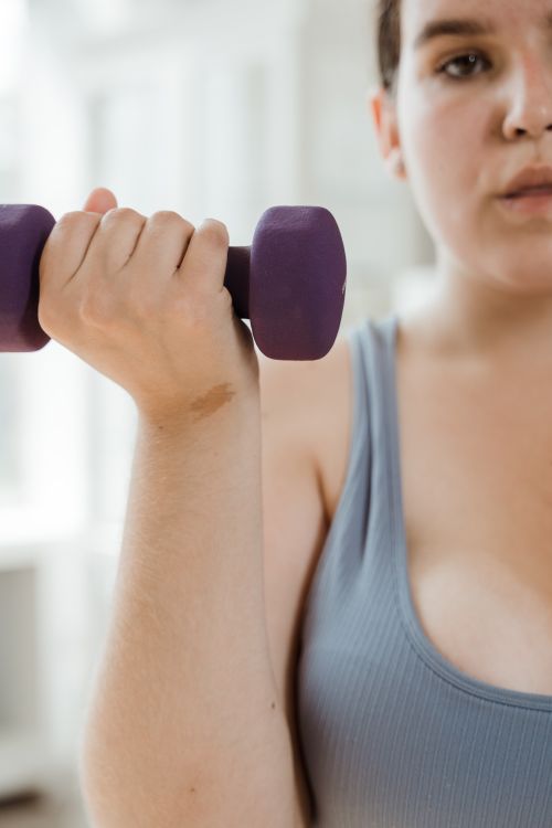 Free Close-up of a plus size woman lifting a dumbbell, promoting fitness and body positivity. Stock Photo
