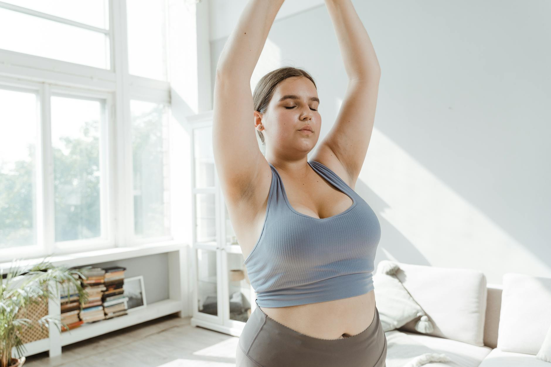 A plus size woman practicing body positivity and stretching at home for a healthy lifestyle.