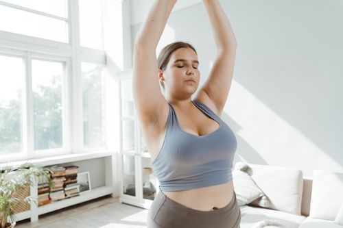 Free A plus size woman practicing body positivity and stretching at home for a healthy lifestyle. Stock Photo
