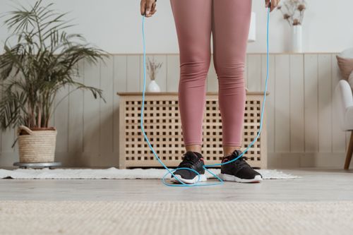 Free Woman in pink activewear exercising indoors with a jump rope. Stock Photo