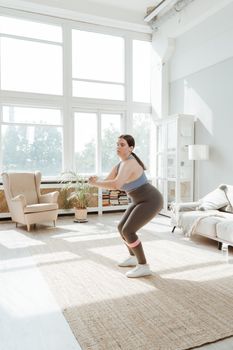 Woman in activewear doing a workout in a sunlit living room, showcasing fitness and health at home.