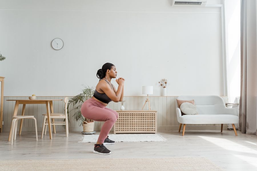 Woman doing squats at home as part of a weight plan
