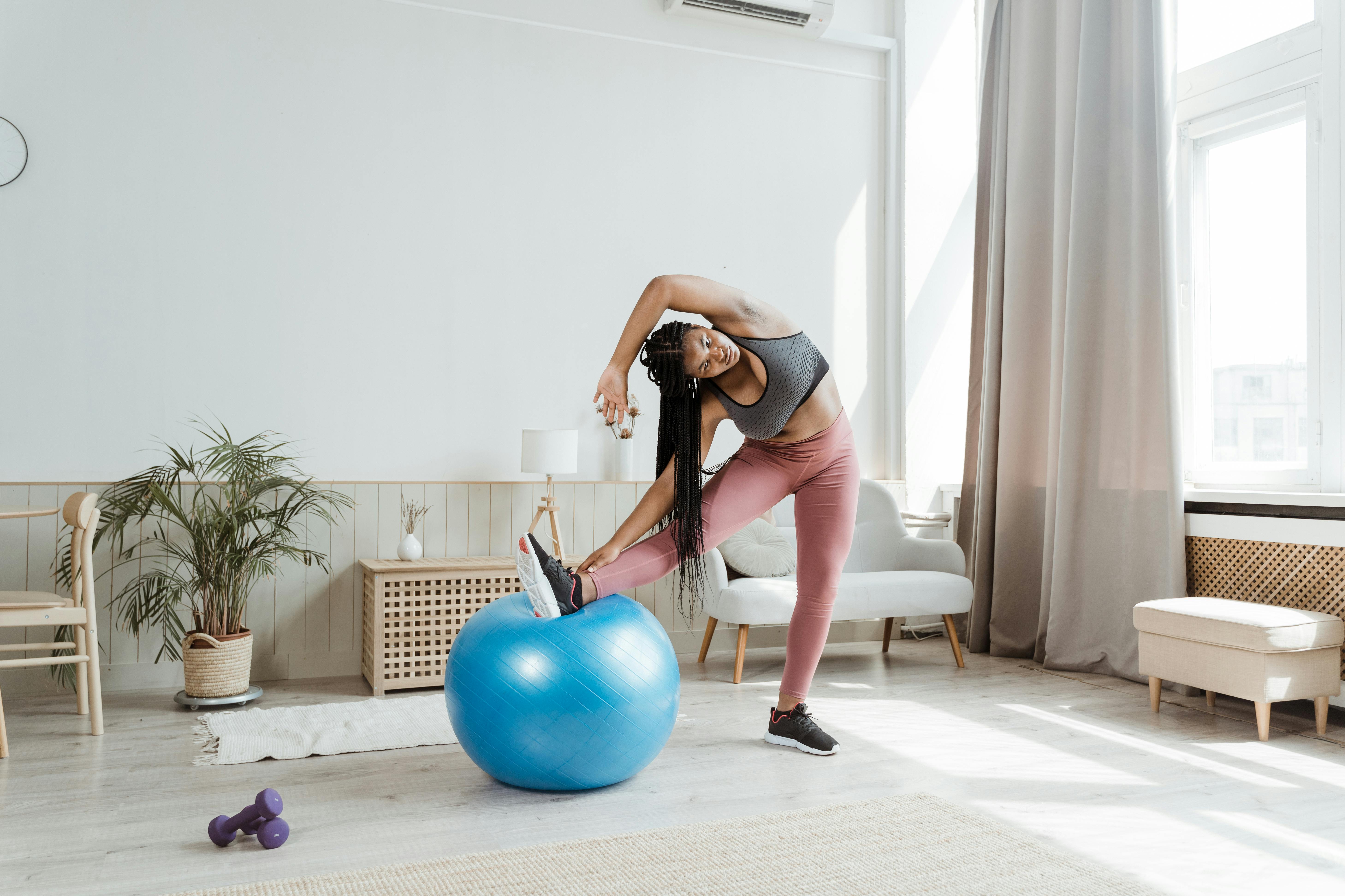 A Woman Stretching with Her Leg on an Exercise Ball · Free Stock Photo