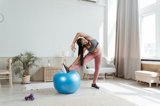 African American woman engages in fitness routine with exercise ball indoors.