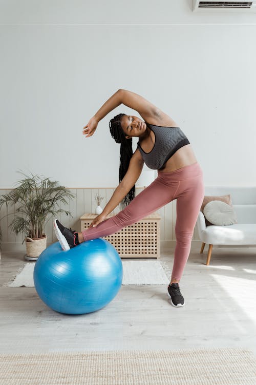 Woman in Black Top and Pink Leggings Warming Up with Blue Fit Ball
