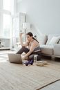 Woman in Sportswear Sitting on Floor Using Laptop and Eating Doughnut
