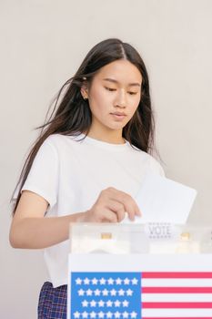 Woman in White Crew Neck Shirt Putting her Vote on Ballot Box