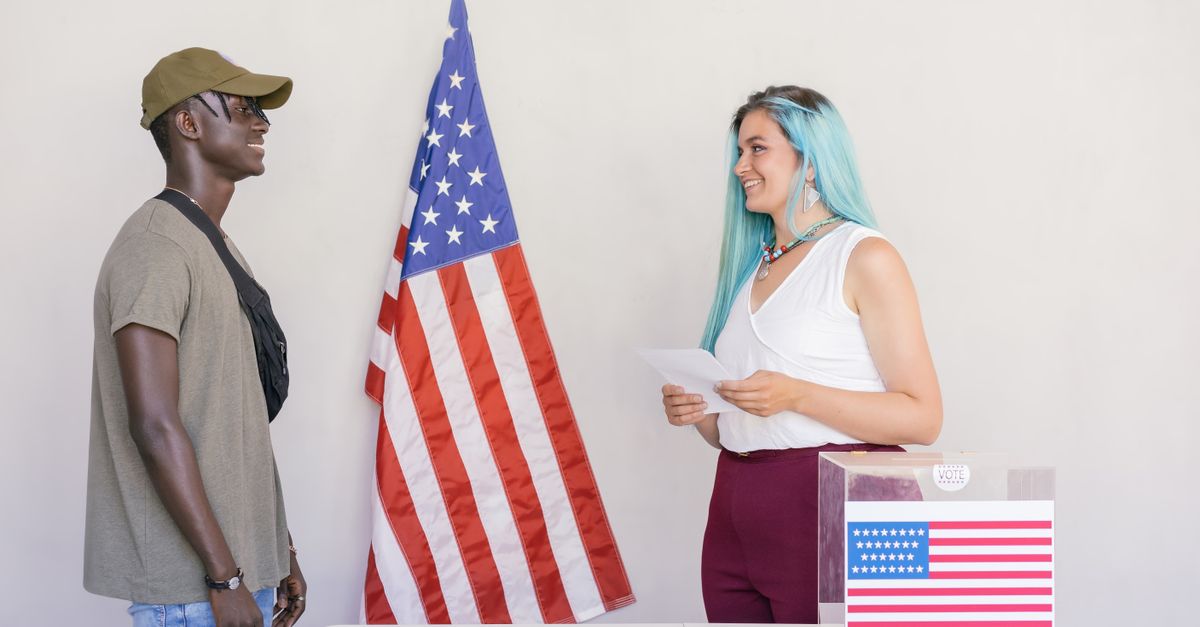 Two diverse young adults engaging in a voting process next to an American flag.