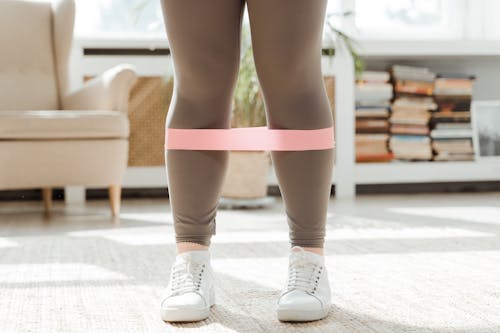 Woman's Legs in Gray Leggings and White Sneakers with Pink Rubber Strength Band