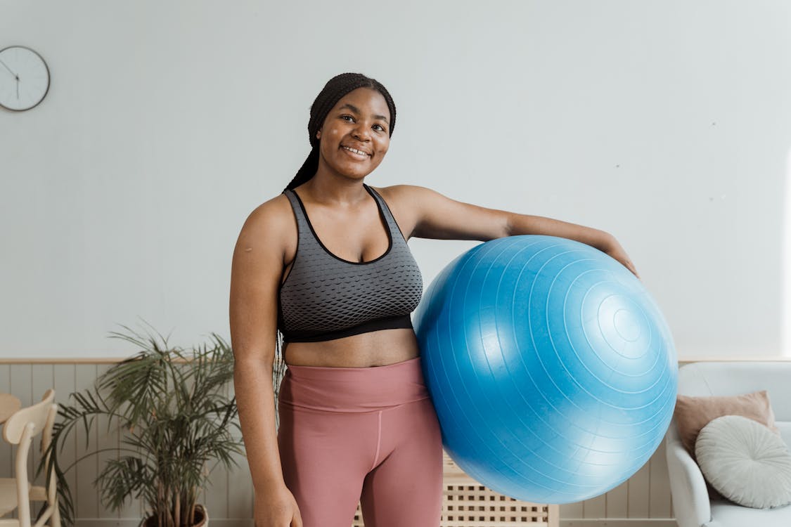 Woman in Gray Sports Bra and Pink Workout Pants Holding A Blue Exercise  Ball · Free Stock Photo