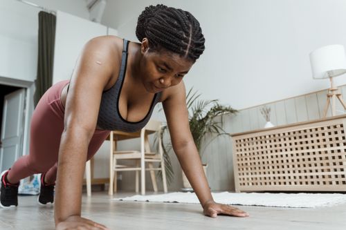 Free Plus-size woman performing push-ups indoors, emphasizing fitness and healthy living. Stock Photo