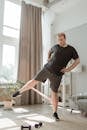 Man in Black T-Shirt and Gray Shorts Doing Leg Exercises with Rubber Strength Band