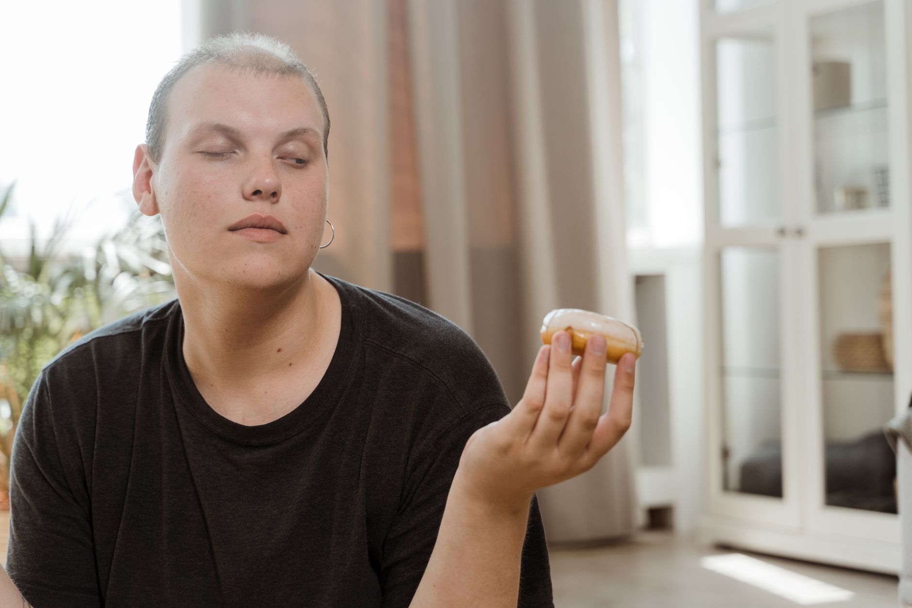 減重失敗不是你的錯:系統設計才是成功關鍵 Young adult contemplating a donut while sitting indoors, showcasing a thoughtful expression.