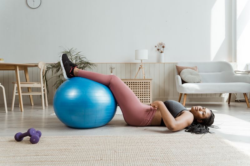 Woman on exercise ball performing fitness routine in modern living room.