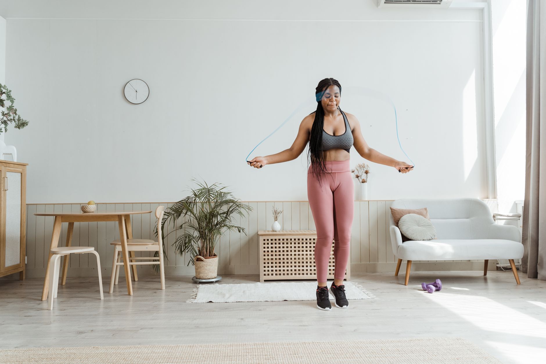 簡單減重方法:日常技巧讓你輕鬆瘦身 Confident black woman in activewear jump roping at home, promoting wellness and body positivity.