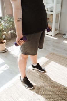 A person holding dumbbells in a well-lit room, focusing on fitness and wellness.