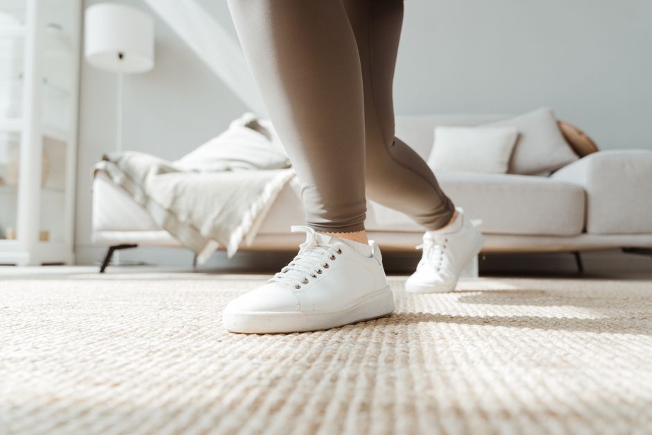 Close-up of a woman stretching in activewear at home, promoting wellness and fitness.