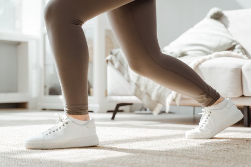 Free Close-up of a woman stretching at home in sportswear and sneakers. Stock Photo