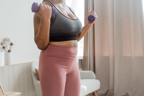 Free A woman in activewear working out indoors with dumbbells for fitness and wellness. Stock Photo