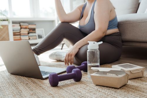 Free Plus size woman exercising at home with purple dumbbells, showcasing healthy lifestyle. Stock Photo