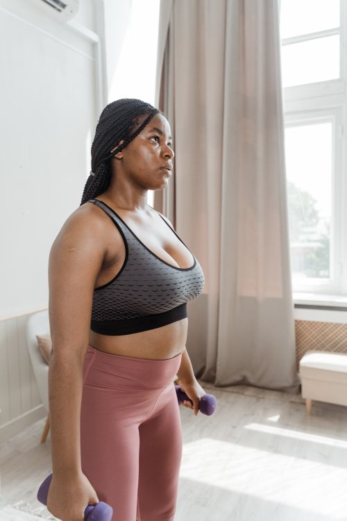 Free Fit black woman lifting dumbbells indoors, promoting fitness and wellness. Stock Photo