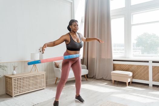 A woman hula hooping indoors, focusing on fitness and wellness in a modern setting.