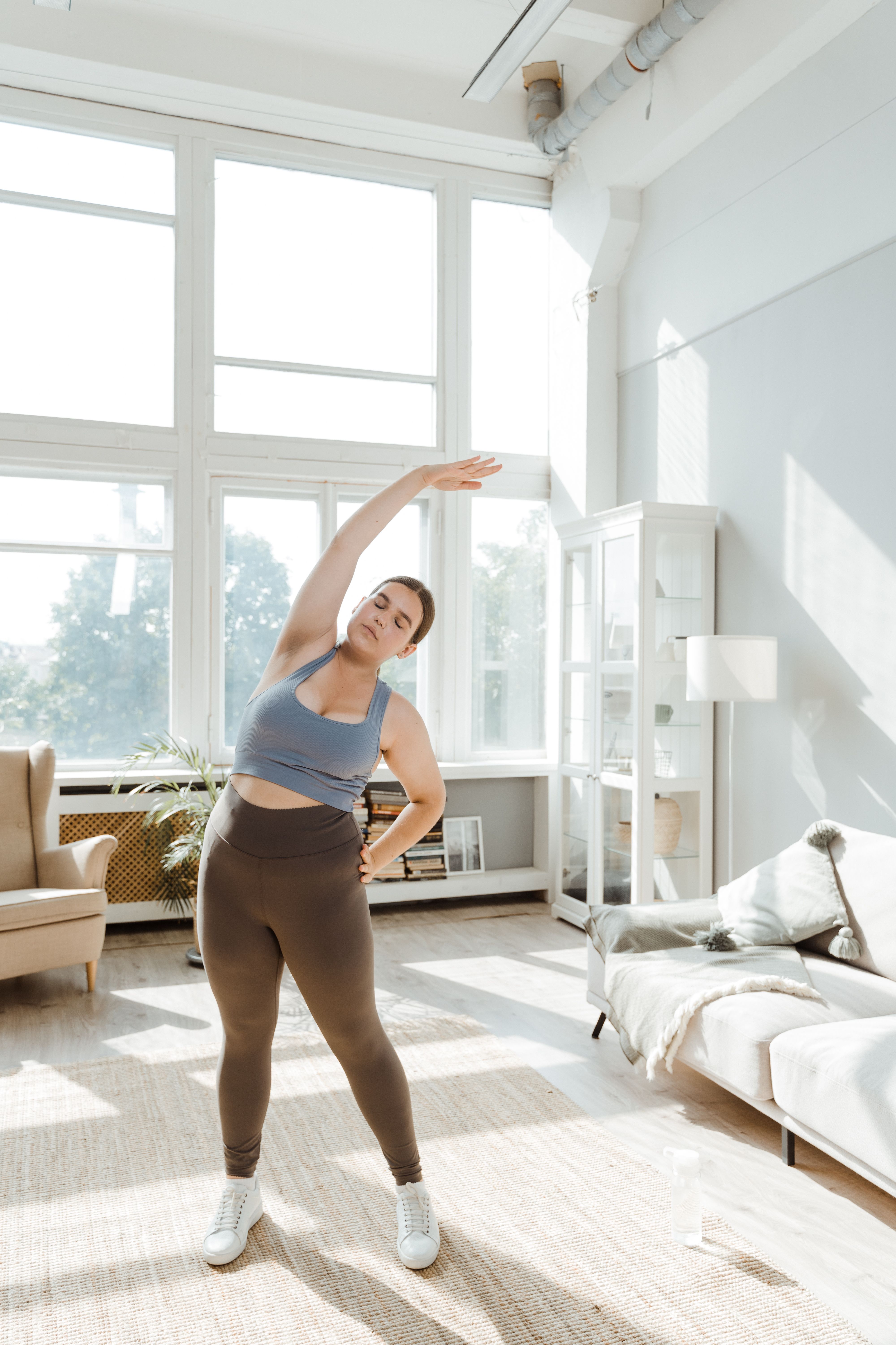 Woman in a side bend in a bright living room, photo by MART PRODUCTION on Pexels