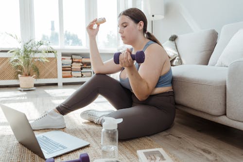 Woman Holding a Donut and a Dumbbell