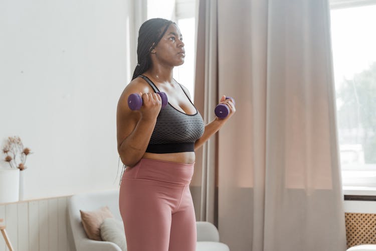 A Woman Lifting Dumbbells At Home