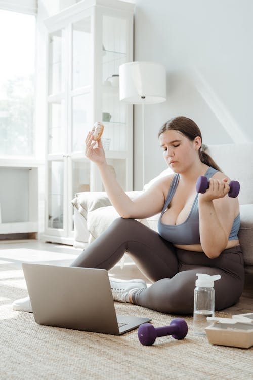 Free Woman Watching on Laptop while using a Dumbbell Stock Photo