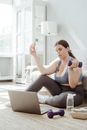 Woman in Blue Tank Top and Black Leggings Sitting on White Bed
