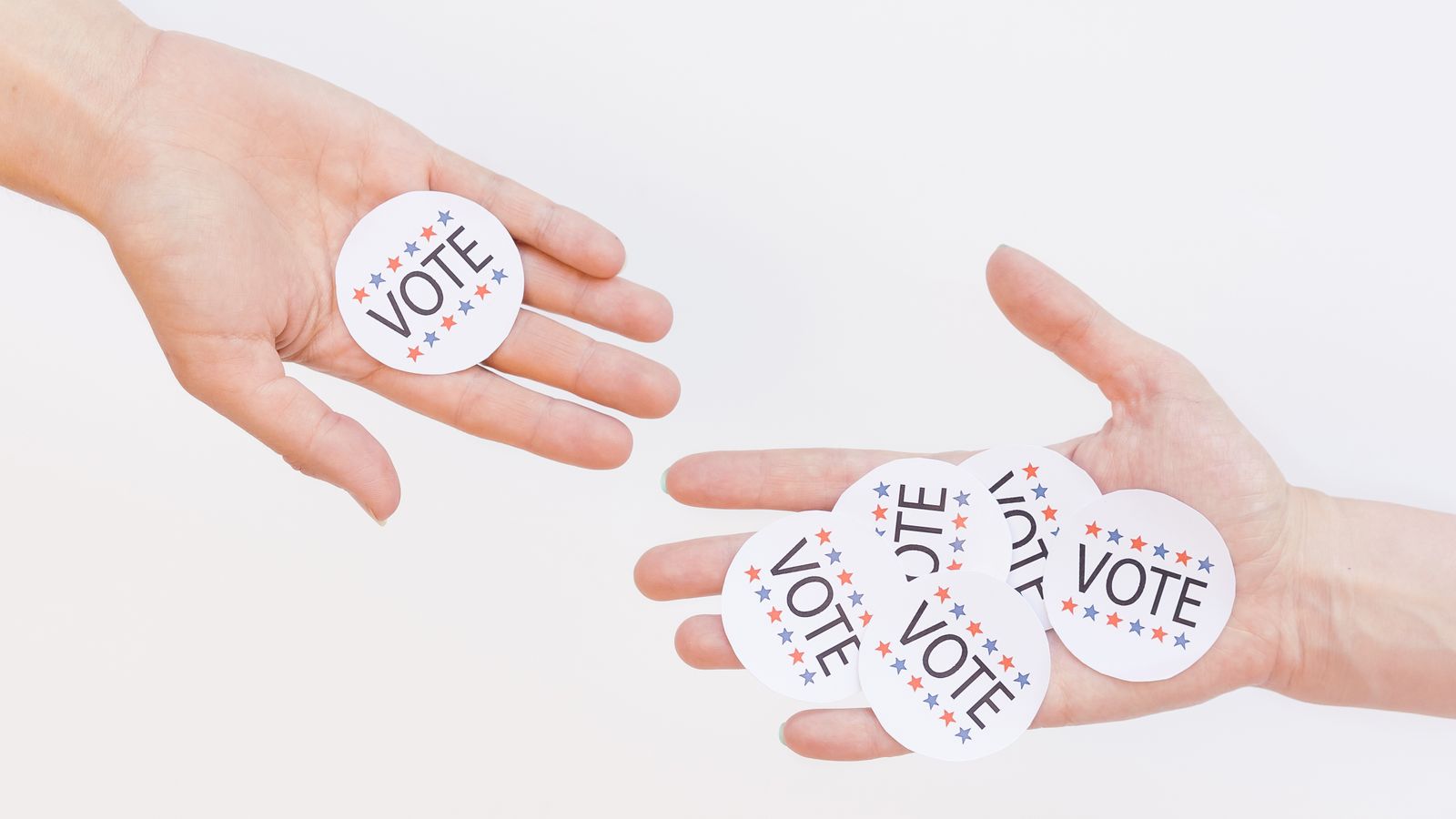 Close-up of hands holding election vote stickers, symbolizing participation.