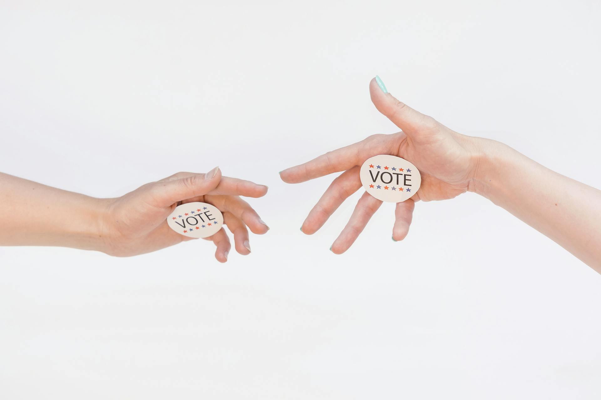 Two hands exchanging vote stickers symbolizing political participation and civic duty.