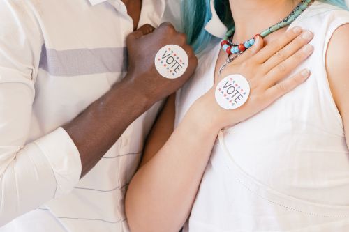 Free Close-up of two diverse individuals showing their commitment to voting with stickers. Stock Photo