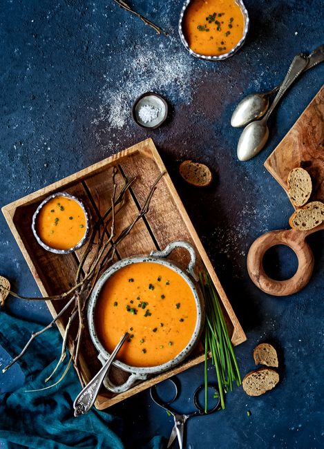 A stylish flat lay of creamy pumpkin soup in bowls with croutons on a wooden tray, perfect for culinary presentations.