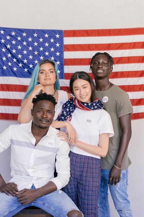 Free A multicultural group poses proudly with the American flag, symbolizing unity and diversity. Stock Photo
