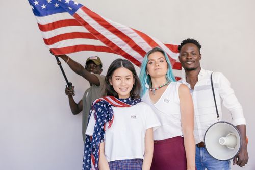 Free Multiracial group celebrating with the American flag, promoting unity and patriotism. Stock Photo