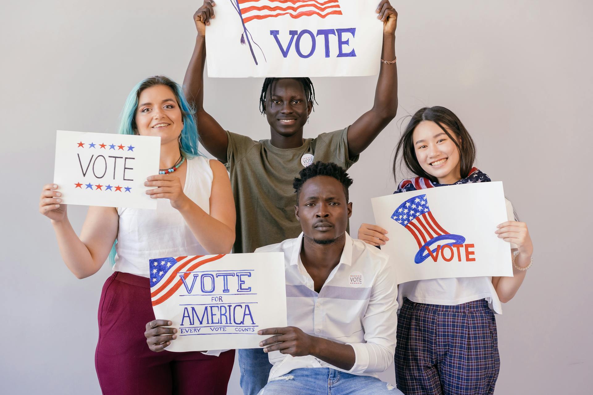 Diverse group of young adults proudly holding signs to encourage voting in America.