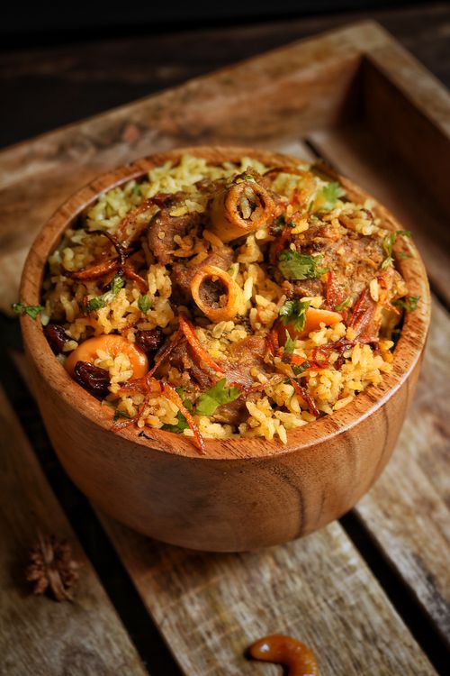 Free Savor the rich flavors of traditional biryani with spices and herbs in a rustic wooden bowl. Stock Photo