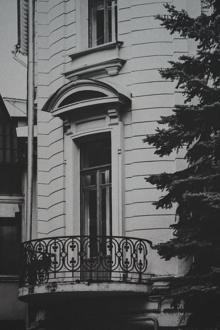A striking black and white photo showcasing a building's ornate balcony and window facade.