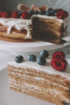 Scrumptious layered cake topped with fresh raspberries and blueberries.