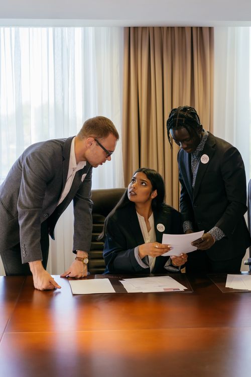 Free Three diverse professionals collaborate seriously in a meeting room, discussing important documents. Stock Photo