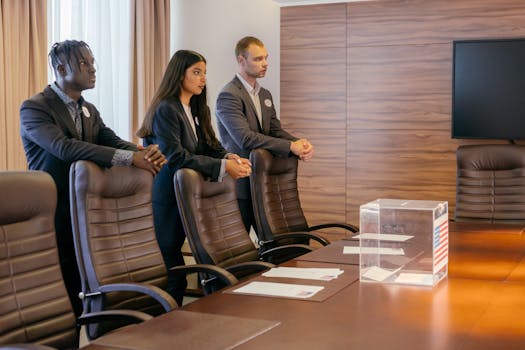 A diverse group of professionals discuss around a ballot box in a conference room.