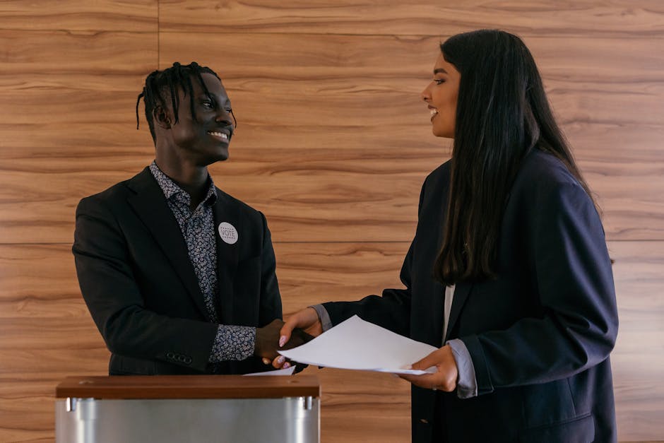 Two diverse politicians shaking hands while discussing a campaign indoors.
