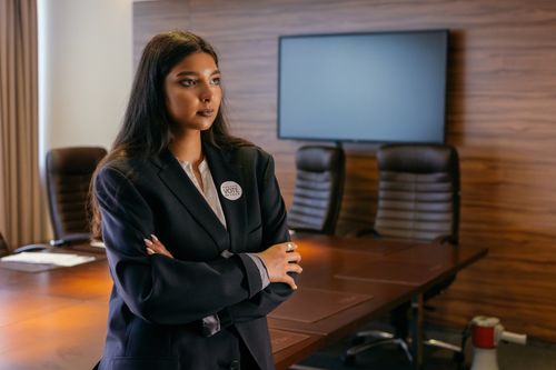 Free A confident woman in a business suit stands with arms crossed in a corporate boardroom. Stock Photo