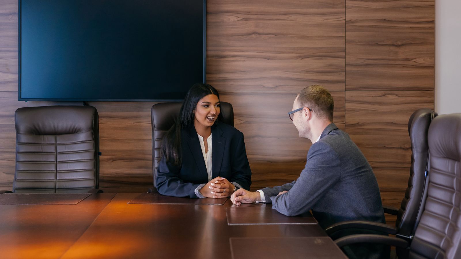 Two colleagues engage in a business discussion in a modern conference room.